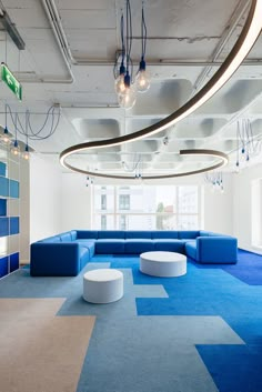 an office with blue and white carpet, round couches and chandeliers hanging from the ceiling