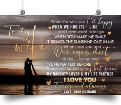 a wooden sign with the words i love you and two people standing in water at sunset