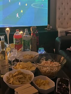 a table full of snacks and drinks in front of a flat screen tv