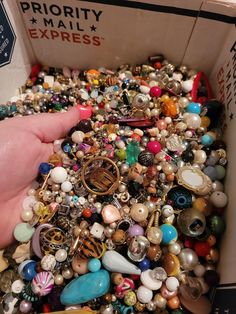 a box filled with lots of different types of beads and jewelry on display in someone's hand