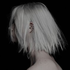 the back of a woman's head with white hair and piercings on it