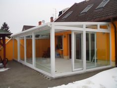 an orange house with white trim and glass doors on the outside, surrounded by snow