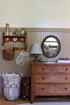 a dresser with two baskets and a mirror on it next to a wall mounted shelf