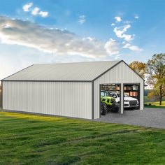 a large metal building with a tractor parked in the driveway next to it and an open garage door