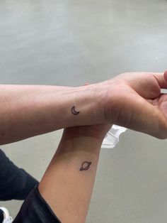 two people holding hands with tattoos on their wrists and one has a crescent tattoo on the wrist