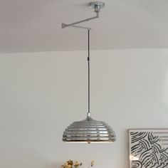 a lamp hanging from the ceiling in a room with white walls and wood furniture on it