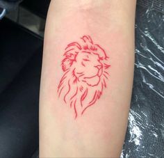 a small red lion tattoo on the arm