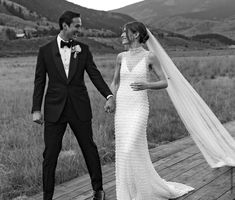 a bride and groom holding hands while standing on a deck