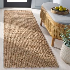 an area rug is on the floor in front of a chair and vase with fruit