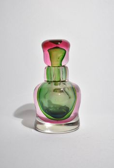 a green and pink glass bottle sitting on top of a white table