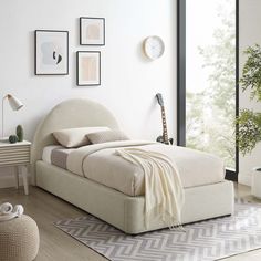 a bedroom with a bed, nightstands and pictures on the wall above it in neutral colors