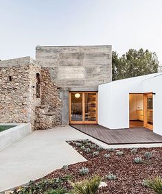 a modern house with stone walls and wooden flooring, surrounded by greenery in the foreground