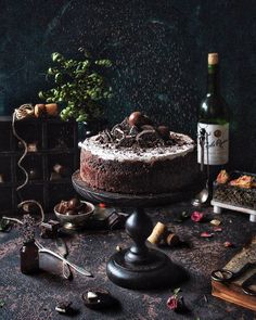 a chocolate cake sitting on top of a table next to wine bottles and other items