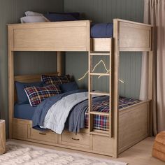 a wooden bunk bed with blue sheets and plaid pillows on it's bottom shelf