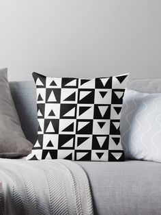 a black and white pillow sitting on top of a gray couch next to two pillows