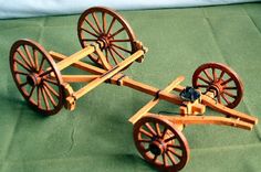 a wooden toy with wheels on a green cloth