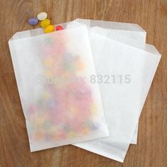 three white paper bags with candy on them sitting on top of a wooden table next to each other