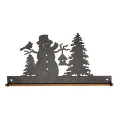 a metal snowman with trees and bells on a shelf in front of a white wall