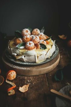 a cake sitting on top of a wooden table covered in powdered sugar and oranges