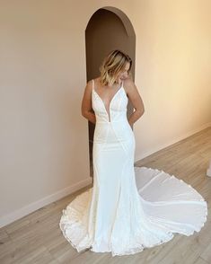 a woman in a white wedding dress standing next to a wall and looking at her reflection