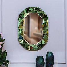 a mirror sitting on top of a white wall next to vases and flowers in front of it