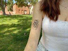 a woman with a tattoo on her arm standing in the grass next to a tree