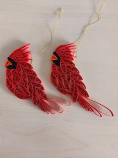 two red birds made out of paper sitting on top of a table