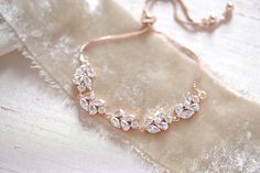 a rose gold bracelet with crystal stones on it's side, sitting on a white cloth