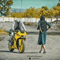 a woman standing next to a man on a yellow motorbike in the road