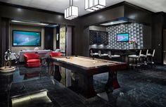 a room with a pool table, chairs and a flat screen tv on the wall