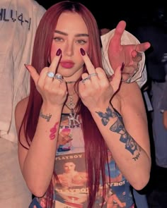 a woman with red hair holding two fingers up in front of her face and making the peace sign