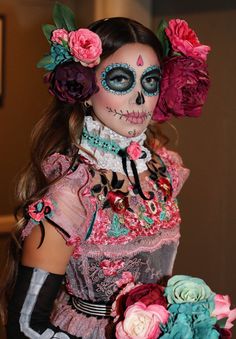 a woman with makeup and flowers in her hair is wearing a skeleton make - up