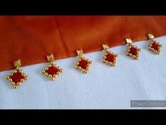 four pairs of earrings with red stones in gold tone setting on white fabric, closeup