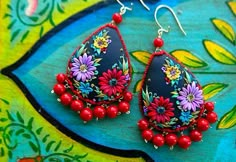 a pair of earrings with beads and flowers on them sitting on top of a table