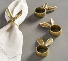 napkin rings with gold leaves on them sitting next to a white napkin and two napkins