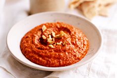 a white bowl filled with red sauce and nuts