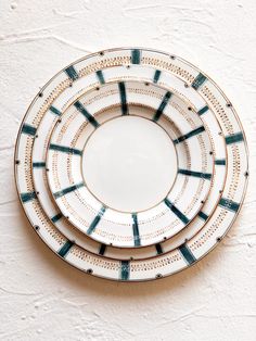 three plates sitting on top of each other in front of a white wall with blue and green designs