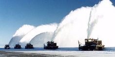 several snowplows are spraying water onto the ground