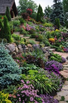 a garden filled with lots of different types of flowers and plants next to a house