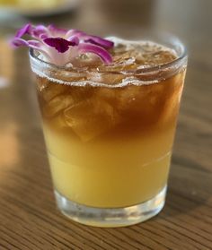 a close up of a drink on a table with flowers in the glass and ice