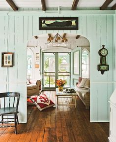 a living room filled with furniture and a clock mounted to the side of it's wall