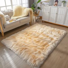 a living room filled with furniture and a white rug on top of a hard wood floor