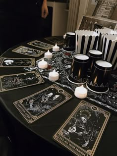 a table topped with cards and candles on top of a black cloth covered tablecloth