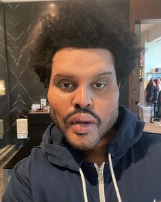 a man with an afro is taking a selfie in front of a mirror and looking at the camera