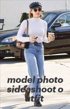 a woman walking down the street while holding a cup and cell phone in her hand