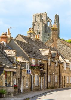 an old european street with stone buildings in the foreground and a castle in the background