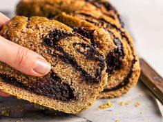 a person is holding a chocolate swirl bread