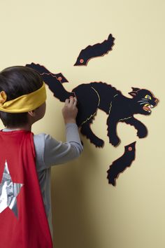 a young boy wearing a bandana and making a paper cut out of a black cat