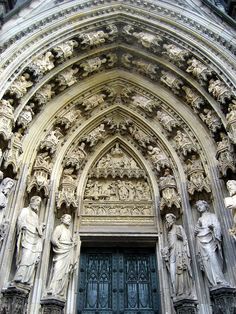 an ornate building with statues on the front and side doors, in gothic style architecture