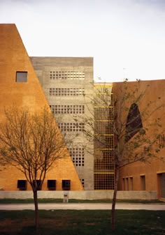 two trees in front of an orange building with geometric designs on the walls and windows